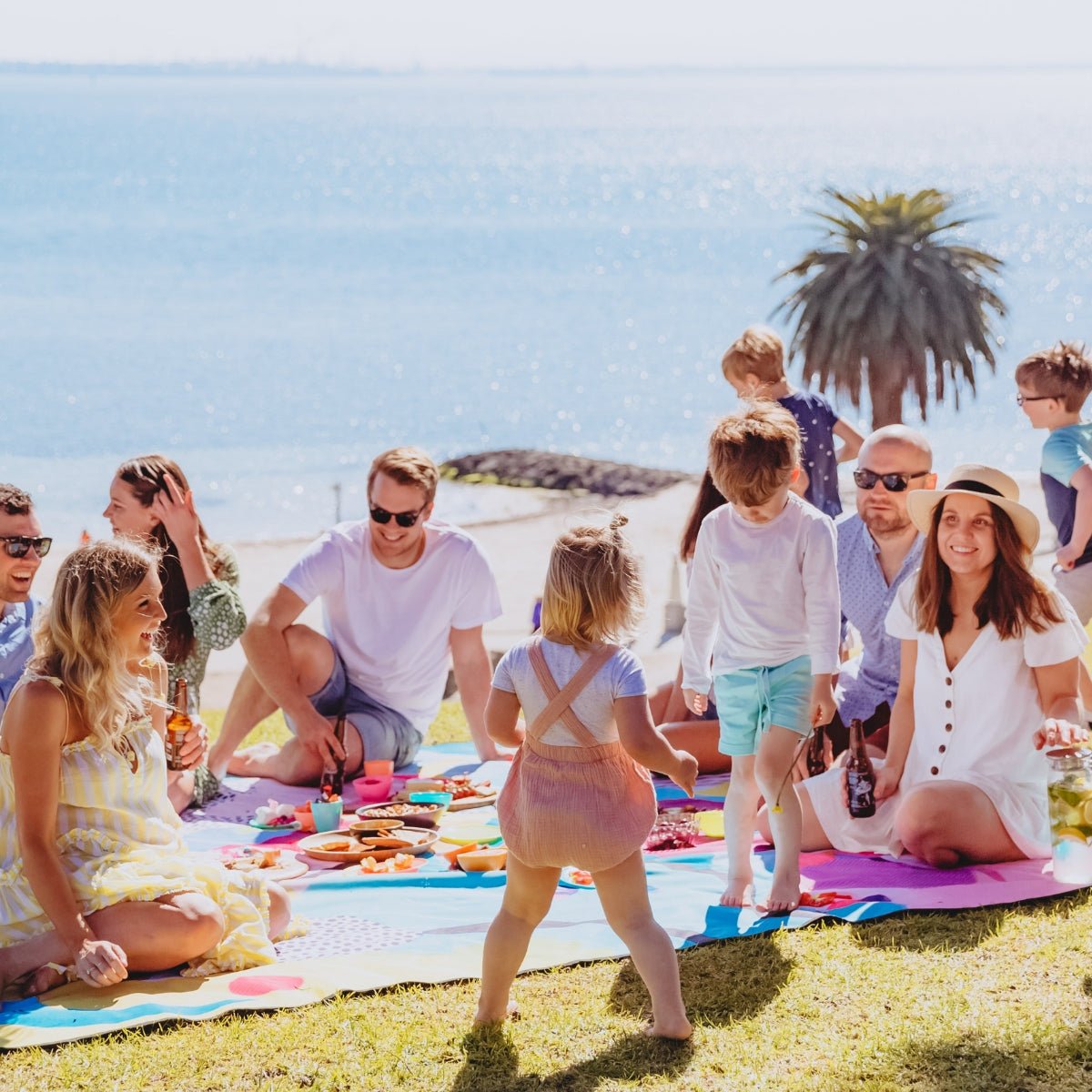 adults and kids sitting on really big picnic rug in sunshine